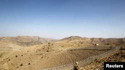 FILE - A soldier stands guard along the border fence outside the Kitton outpost on the border with Afghanistan in North Waziristan, Pakistan, Oct. 18, 2017.