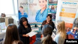 FILE - Job seekers listen to a recruiter at the Colorado Hospital Association job fair in Denver, Colorado, Oct. 4, 2017. 