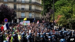 A man in a crowd holds a poster on which is written, "Our liberties pass away," during a protest against the COVID vaccine and vaccine passports, in Paris, Aug. 7, 2021. 