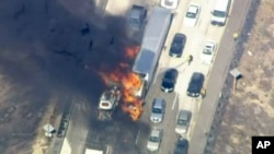 In this frame from video provided by NBC4, smoke rises from vehicles as a fast-moving wildfire swept across a freeway near Hesperia, Calif., July 17, 2015.