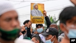 A supporter holds up a poster bearing a portrait of firebrand cleric Rizieq Shihab during a rally near the district court where his sentencing hearing is held in Jakarta, Indonesia, June 24, 2021. 