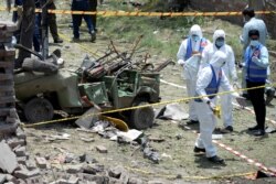 FILE - Members of the Counter Terrorism Department (CTD) survey the site after a deadly blast in residential area in Lahore, Pakistan, June 23, 2021.