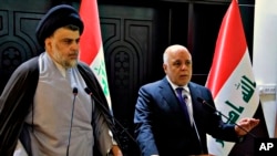 FILE - In this photo provided by the Iraqi government, Iraqi Prime Minister Haider al-Abadi, right, and Shiite cleric Muqtada al-Sadr hold a press conference in Baghdad, Iraq, May 20, 2018. 