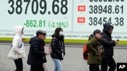 টোকিওতে একটি সিকিউরিটিজ ফার্মে জাপানের নিক্কেই সূচক দেখানো একটি ইলেক্ট্রনিক স্টক বোর্ডের সামনে লোকজন হাঁটছে। ৩ ফেব্রুয়ারি, ২০২৫।