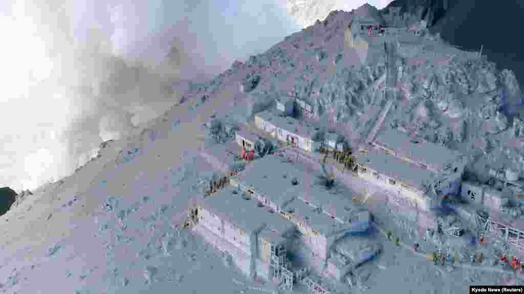 Japan Self-Defense Force (JSDF) soldiers and firefighters conduct rescue operations at mountain lodges, covered with volcanic ash as volcanic smoke rises near the peak of Mount Ontake, which straddles Nagano and Gifu prefectures, Sept. 28, 2014.