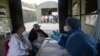 Mujeres escuchan a un trabajador de la salud mientras son examinadas para detectar COVID-19 en un hospital de campaña instalado en el estacionamiento del auditorio Poliedro de Caracas, en Venezuela. Marzo 21, 2021.
