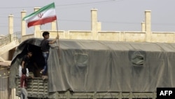 FILE - A Syrian boy holds the Iranian flag as a truck carrying aid provided by Iran arrives in the eastern city of Deir el-Zour, Sep. 20, 2017.