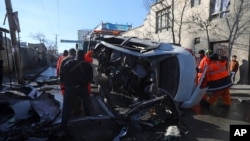 Afghan security personnel and municipality workers remove a damaged vehicle after a roadside bomb attack in Kabul, Dec. 22, 2020. 