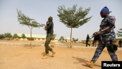 FILE - Police officers walk at the JSS Jangebe school, a day after over 300 school girls were abducted by bandits, in Zamfara, Nigeria, Feb. 27, 2021. 