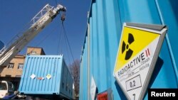 FILE - Workers place a container with spent highly-enriched uranium on a truck bound for Russia, at a nuclear research facility in Kyiv, March 24, 2012.