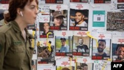 ทหารเดินผ่านโปสเตอร์ชาวอิสราเอลที่หายไป บริเวณ Hostages Square ในเทลอาวีฟ อิสราเอล เมื่อ 12 ก.พ. 2024 (เอเอฟพี)