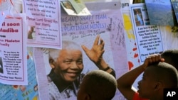 Anak-anak Afrika Selatan membaca pesan-pesan dan doa kesembuhan bagi Nelson Mandela, di luar rumah sakit Pretoria, di mana Mandela dirawat (1/7). 