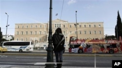 A woman stands opposite the Parliament in central Athens, Tuesday, Nov. 27, 2012. 