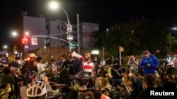 FILE - People watch as police arrest protesters for breaking a curfew during a solidarity rally calling for justice over the death of George Floyd, June 5, 2020, in the Brooklyn borough of New York. 