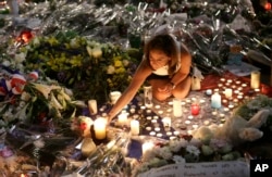 A woman lights candles at a new memorial in a gazebo in a seaside park on the famed Promenade des Anglais in Nice, southern France, July 18, 2016.