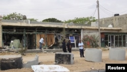 FILE - A man cleans his shop after a suicide car bomber blew himself up at a checkpoint in Dafniya outside Mistrata, Libya, May 31, 2015.