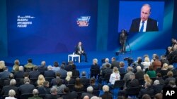 Russian President Vladimir Putin, sitting on the stage at centre rear, speaks to his supporters during a meeting for his campaign in Moscow, Jan. 30, 2018. 