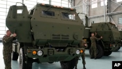 FILE - Polish soldiers look at a vehicle carrying one of the U.S.-made HIMARS rocket launchers, at an air base in Warsaw, Poland, on Monday, 15 May 2023. U.S. officials said that a military aid package for Ukraine would include munitions for HIMARS.