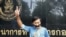 Thai journalist Pravit Rojanaphruk flashes a V-sign as he stands with his mouth taped outside a military base in Bangkok where he had been summoned by the junta, May 25, 2014.