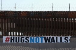A "#HUGS NOT WALLS" banner is displayed along the border wall as part of 8th annual event on the Rio Grande, in Ciudad Juarez, Mexico, June 19, 2021.