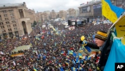 A teenager waves a national flag over a crowd of Pro-European Union activists gathered during a rally in the Independence Square in Kyiv, Ukraine, Dec. 8, 2013.