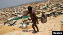 FILE - A Rohingya refugee boy carries water in the Kutupalong refugee camp, in Cox's Bazar, Bangladesh, March 22, 2018. 