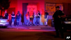 ក្រុមអ្នកឈរមើល​នៅ​ខាងក្រៅ​ហាង​មួយ​ដែល​មាន​បិត​បន្ទះ​ក្តារ​នៅ​លើ​បង្អួច​និង​ទ្វារ ខណៈ​ដែល​ក្រុម​អ្នកតវ៉ា បាន​ប៉ះទង្គិច​ជាមួយ​ប៉ូលិស​នៅ​ល្ងាច​ថ្ងៃអង្គារ ទី២៥ ខែសីហា ឆ្នាំ២០២០ នៅ​ទីក្រុង Kenosha រដ្ឋ Wisconsin។ 