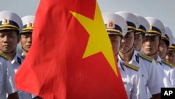FILE - Vietnam People's Navy personnel carry their country's national flag.