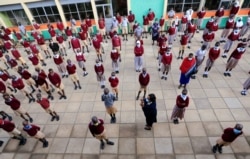 A teacher talks to schoolchildren at the morning parade at the Toi Primary School during the reopening of schools, after the government closed learning institutions, in Kibera district of Nairobi, Kenya, Jan. 4, 2021.