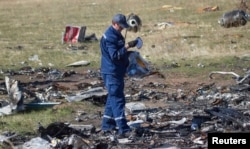 FILE - An Emergencies Ministry member searches for belongings at the site where the downed Malaysia Airlines flight MH17 crashed, near the village of Hrabove (Grabovo) in Donetsk region, eastern Ukraine, October 13, 2014.