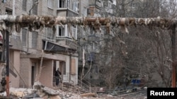 A resident smokes near his apartment building damaged by Russian military strikes, amid Russia's attack on Ukraine, in the frontline town of Pokrovsk in Donetsk region, Ukraine, March 6, 2025.