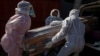 Funeral home workers in protective suits carry the coffin of a woman who died from COVID-19 into a hearse in Katlehong, near Johannesburg, South Africa, July 21, 2020.