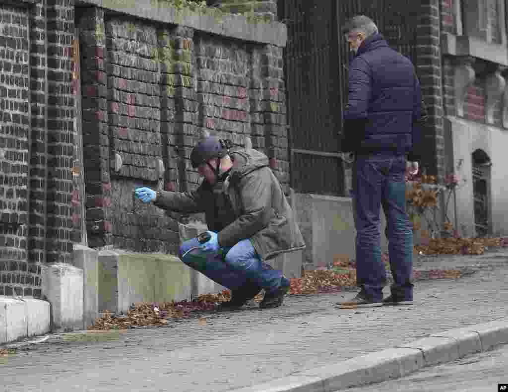 Belgian police officers examine a wall in a street in Verviers. The street was blocked after security forces conducted anti-terrorist raids in Verviers, Belgium, Jan. 16, 2015.