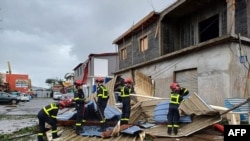 This handout photograph released by the Securite Civile on Dec. 15, 2024 and taken at an undisclosed location on Mayotte shows members of the French Civil Security cleaning debris after the cyclone Chido hit the archipelago.