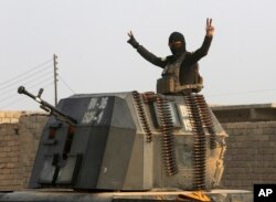 A member of Iraq's elite counterterrorism forces in a military convoy flashes a victory sign as forces advance toward Islamic State positions in the village of Tob Zawa, about 9 kilometers (5½ miles) from Mosul, Iraq, Oct. 25, 2016.