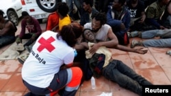A Spanish Red Cross worker aids African migrants after they crossed a border fence between Morocco and Spain's north African enclave of Ceuta, Oct. 31, 2016.