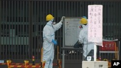 Guards read a whiteboard near the Fukushima-1 nuclear plant's main gate, Futaba, Japan