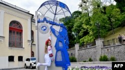 Дівчинка біля скульптурної композиції "Українка під парасолькою НАТО" творчої майстерні ARTBUZ під час святкування Дня вишиванки у Києві 16 травня 2024 року. Sergei SUPINSKY/AFP