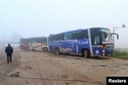 A man walks near buses carrying people evacuated from the two villages of Kefraya and al-Foua, after an agreement reached between rebels and Syria's army, at insurgent-held al-Rashideen, Aleppo province, Syria, April 14, 2017.