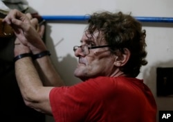 Suspected child webcam cybersex operator David Timothy Deakin, from Peoria, Illinois, waits following his arrest as investigators gather evidence during a raid at his home in Mabalacat, Philippines, April 20, 2017.