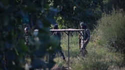 FILE - Indian security force personnel walk past the grave of Syed Ali Shah Geelani, a Kashmiri veteran separatist politician, at a graveyard in Srinagar, September 3, 2021.