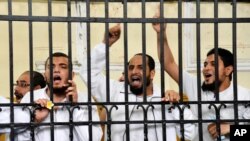 FILE - Supporters of the Muslim Brotherhood and other Islamists call out from the defendants cage as they receive sentences in a mass trial in Alexandria, Egypt, May 19, 2014. 
