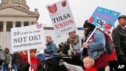 Keagan Nedrow, left, and Reed Nedrow, bottom right, stand with their mother, Tara Nedrow, right, who teaches history at Union High School, and other teachers, during a teacher rally against low school funding at the state Capitol Oklahoma City, Monday, Ap