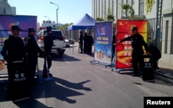 FILE - Police with riot gear guard a checkpoint on a road near a courthouse where ethnic Uighur academic Ilham Tohti's trial is taking place in Urumqi, Xinjiang Uighur Autonomous Region, Sept. 17, 2014.