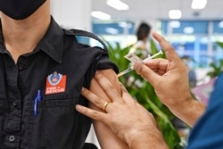 In this May 10, 2021, file photo, a Fire and Rescue worker receives a Pfizer vaccine at the newly opened COVID-19 vaccination center in Sydney, Australia.