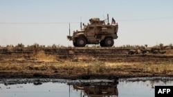 A US armoured vehicle drives past an oil field in the countryside of al-Qahtaniyah town in Syria's northeastern Hasakeh province near the Turkish border, on Aug. 4, 2020.