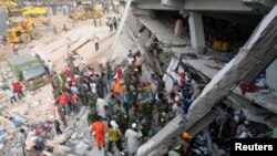 Petugas pemadam kebakaran, tentara dan warga setempat berupaya untuk menyelamatkan pekerja pabrik konveksi yang terperangkap diantara reruntuhan gedung Rana Plaza yang roboh di Savar, 30 kilometer dari Dhaka, Bangladesh (25/4).