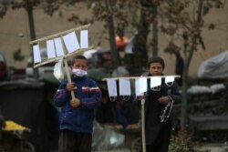 FILE - Street vendors selling protective masks to help curb the spread of the new coronavirus wait for customers in Kabul, Afghanistan, April 14, 2020.