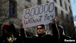 Seorang demonstran mengangkat papan bertuliskan "800 Ribu (Pegawai Federal) Tidak Gajian" akibat 'Shutdown' dalam aksi "Protes (untuk) Akhiri 'Shutdown'" di Washington, 10 Januari 2019.