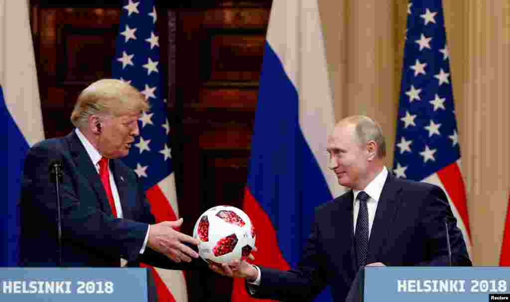 U.S. President Donald Trump receives a football from Russian President Vladimir Putin during their joint news conference after their meeting in Helsinki, Finland.